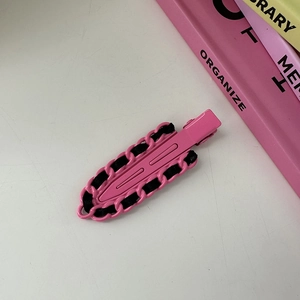 Detalle de pinza para el pelo Y2K rosa brillante con textura de cadena y cinta negra en fondo