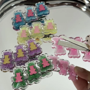 Détail de barrettes ours Y2K colorées en acrylique pailleté sur plateau métallique