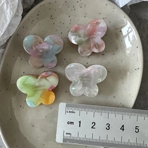 Mini acetic acid butterfly hair clips in four gradient marble colors with gold branding