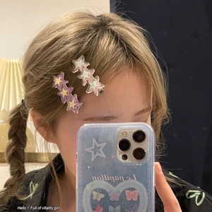 Détail de barrettes étoile Y2K en résine avec paillettes sur les cheveux du modèle