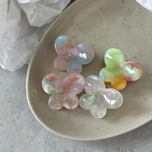Close-up of four colorful gradient butterfly hair clips on a ceramic plate