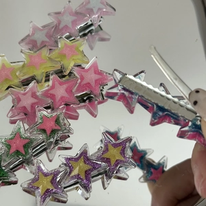 Gros plan de pinces à cheveux étoiles colorées en résine à paillettes avec clips métalliques