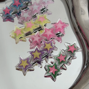 Détail de pinces à cheveux étoiles en acrylique coloré avec paillettes sur un plateau