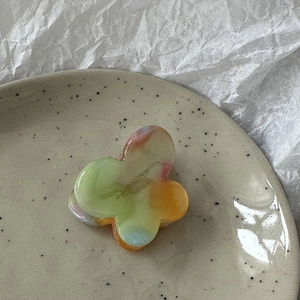Macro detail of butterfly hair claw clip with colorful marble pattern and Sunshine text