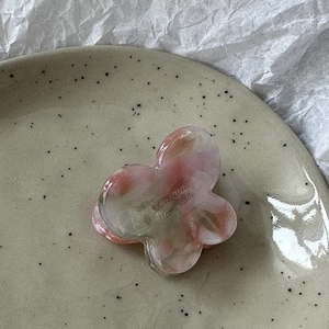 Close-up of marble pattern butterfly hair claw with gold label and handmade text