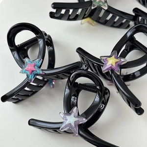 Détail de pinces à cheveux noires ornées d'étoiles pailletées au style Y2K coloré