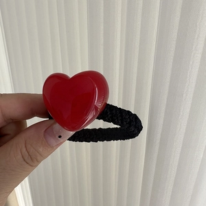 Detailed close-up of a red resin heart hair tie with gold France lettering and black band
