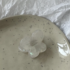 Detailed macro of a butterfly hair clip with iridescent resin finish and handmade logo