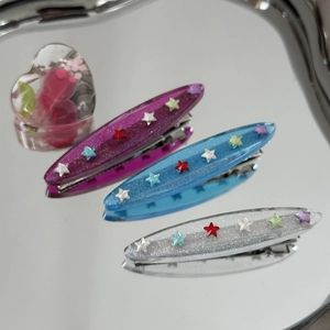 Vue macro détaillée de trois barrettes en résine translucide avec paillettes et mini étoiles