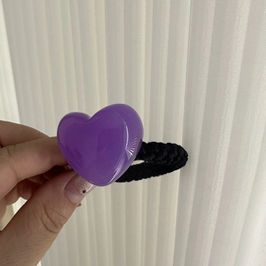 Detail shot of a purple heart-shaped resin hair tie with a black elastic rope