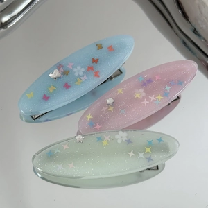 Vue détaillée des barrettes en résine pailletée avec motifs papillons et étoiles