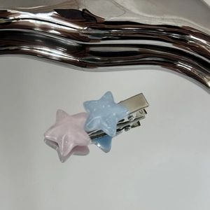 Vue détaillée des barrettes étoiles à paillettes rose et bleu sur une pince argentée