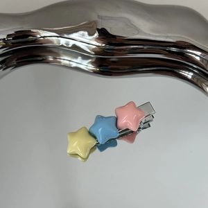 Détail d'une barrette en métal avec trois étoiles en résine aux tons pastel macaron