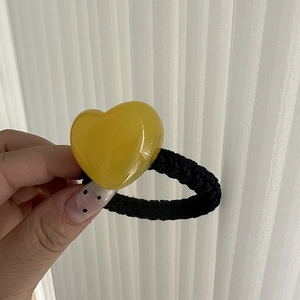 Detailed close-up of a translucent yellow jelly heart resin charm on a thick black hair tie