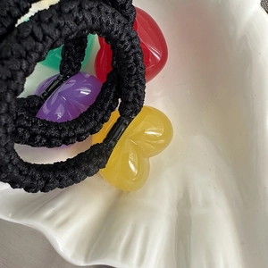 Jelly heart hair ties with colorful resin pendants on black braided ropes in a white shell dish