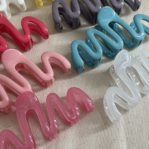 Macro shot of colorful wave-shaped hair claw clips made of smooth premium acrylic