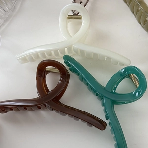 Dettaglio dei fermagli per capelli in resina lucida nei colori crema, caffè e verde