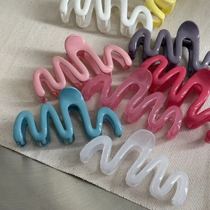 Close-up of colorful wave shaped hair claws in pink blue and white on fabric background