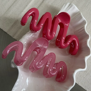 Detail view of wavy hair claws in bright magenta and translucent pink in a shell tray