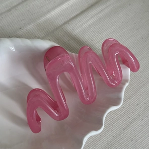 Detailed view of the pink translucent wavy claw clip inside a white shell dish