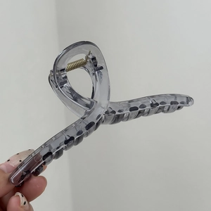 Dettaglio di una molletta per capelli da 14cm grigio fumo traslucido con molla in metallo oro