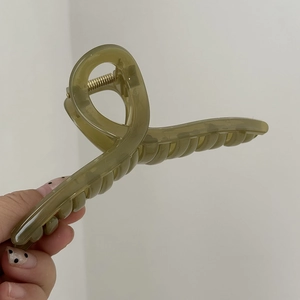 Dettaglio di un fermaglio per capelli traslucido verde oliva da 14cm con molla dorata