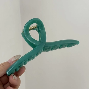 Dettaglio dei denti e della molla dorata di una grande clip per capelli verde opaco