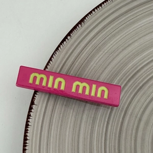 Macro shot of hot pink rectangular hair clip featuring yellow embossed min min letters