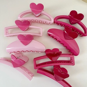 Set of colorful heart-shaped hair claw clips in various pink shades on white background