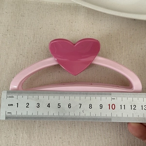 Top view of a 13cm pink heart-shaped hair claw clip next to a measuring ruler