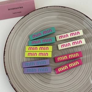 Candy colored acrylic hair clips set with min min artistic lettering on ceramic tray