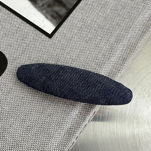 Detailansicht der dunkelblauen Denim-Haarklammer mit Stofftextur und weißen Fasern