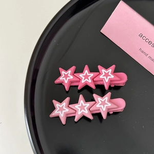Gros plan de barrettes à cheveux étoiles roses avec motifs 3D sur un plateau noir