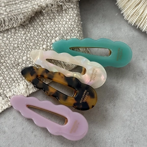 Set of four wave-edged acetate hair clips in mint green, white, tortoiseshell, and lavender