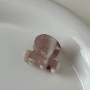 Gros plan sur une mini pince à cheveux effet marbre rose avec texte Amy Bear doré