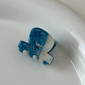 Détail d'une mini pince à cheveux en acétate marbré bleu avec lettrage Amy Bear doré