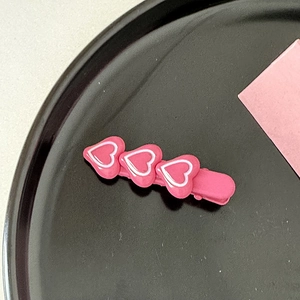 Gros plan d'une barrette à cheveux rose en résine avec trois motifs de cœur