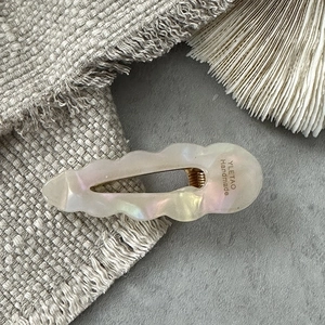 Detailed macro view of pearlescent wave-shaped acetate hair clip with YLETAO engraving