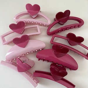 Detail of pink resin hair claws with heart designs in flat lay view on white background