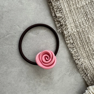 Dettaglio di un elastico per capelli con rosa rosa lucida su sfondo sobrio