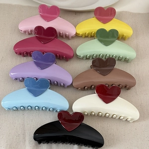 Close-up of nine colorful heart-shaped hair claws in various vibrant dopamine colors