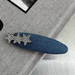 Nahaufnahme einer blauen Denim-Haarklammer mit drei silbernen Sternen und funkelnden Steinen