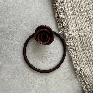 Dettaglio dell'elastico per capelli marrone scuro a forma di rosa con finitura lucida