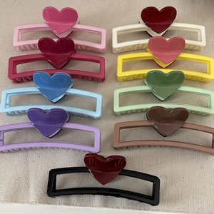 Flat lay of colorful heart-shaped rectangle hair claws in nine vibrant glossy shades
