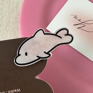 Close-up of a pink dolphin hair clip with a minimalist artistic illustration style
