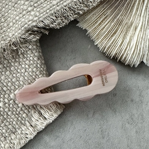 Close-up of pink marbled acetate hair clip with wavy edges and handmade branding