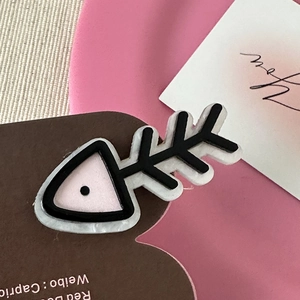 Macro shot of cute cartoon fishbone hair clip in pink and black on gift card
