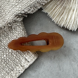 Macro detail of brown wavy hollow water drop hair clip with YLETAO Handmade engraving