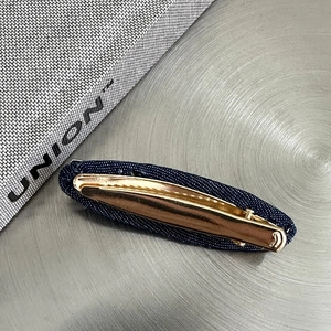 Detailaufnahme der dunkelblauen Denim-Haarklammer mit eleganter goldener Entenschnabelbasis