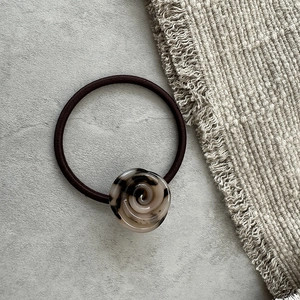 Dettaglio dell'elastico per capelli con bocciolo di rosa marmorizzato su lino